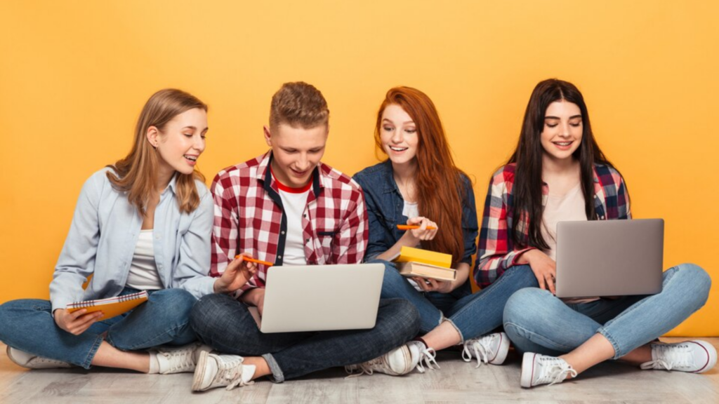 Group of joyful school friends with laptop for searching online learning platforms