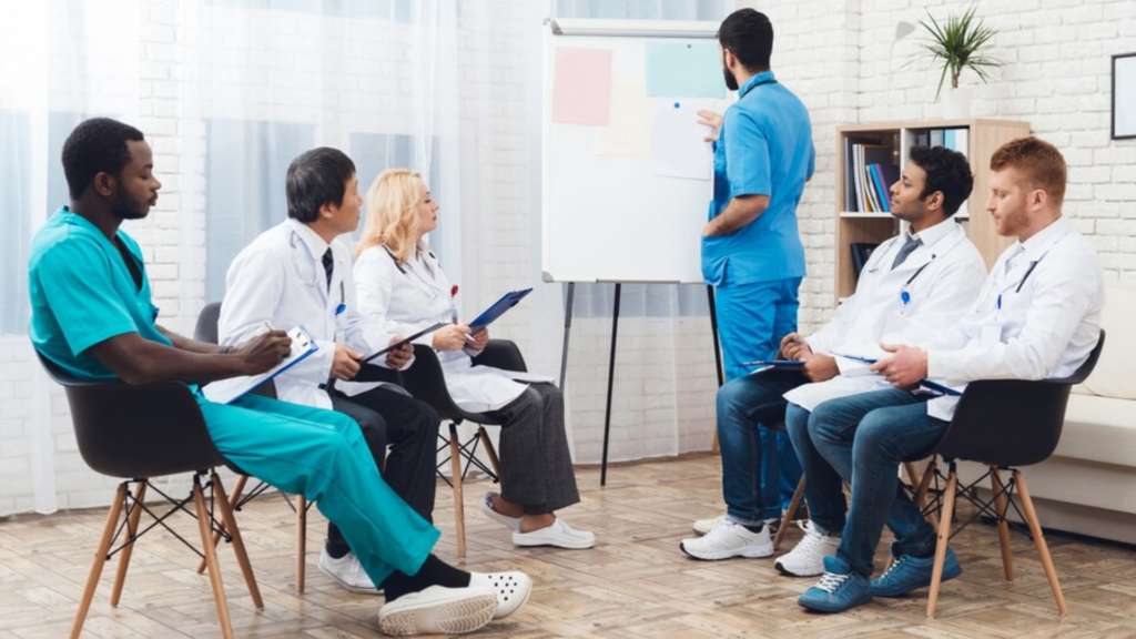 Healthcare professionals in a training session, with one individual presenting at a flipchart while others take notes.