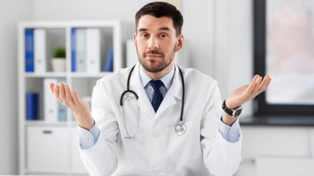 A male doctor in a white lab coat and stethoscope shrugging with open palms, looking directly at the viewer with a questioning or uncertain expression. Keywords: Mental Health Act, section 1 mental health act, section 2 mental health act, section 3 mental health act.