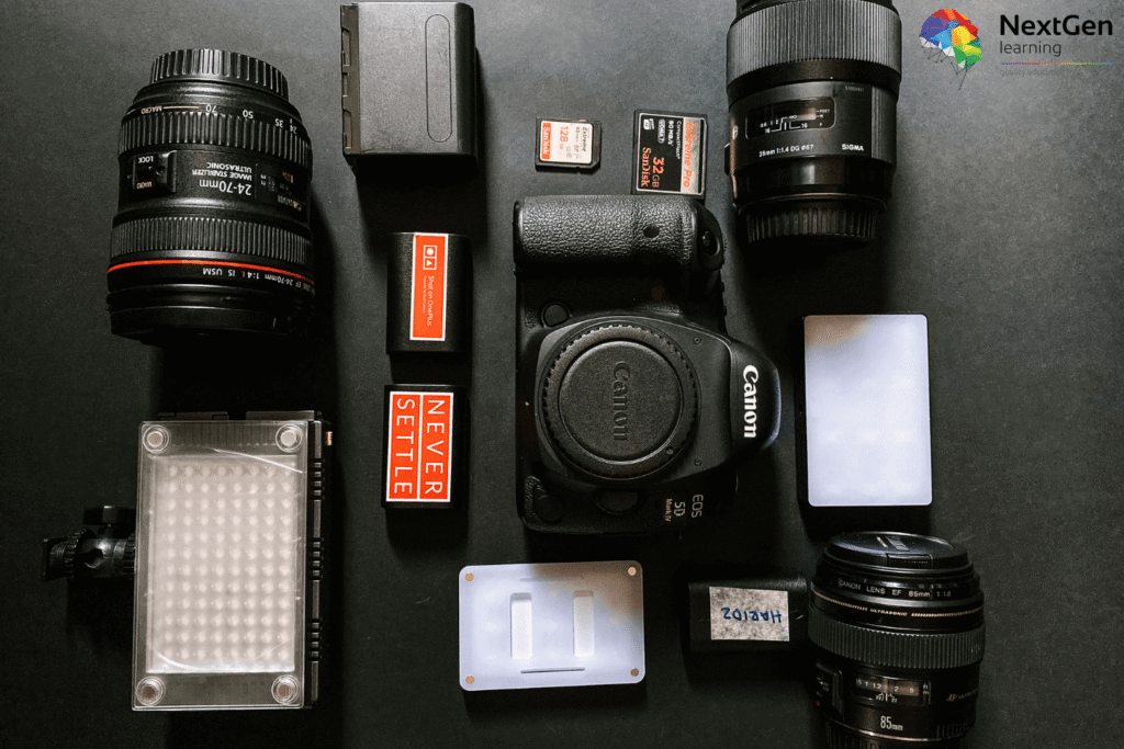 Flat lay image showing beginner photography gear including Canon EOS camera body, multiple lenses, LED light panel, memory cards, battery pack, and power bank, representing essential starter equipment for new photographers.